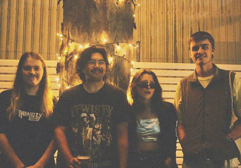 Four people stand in a row and smile at the camera 