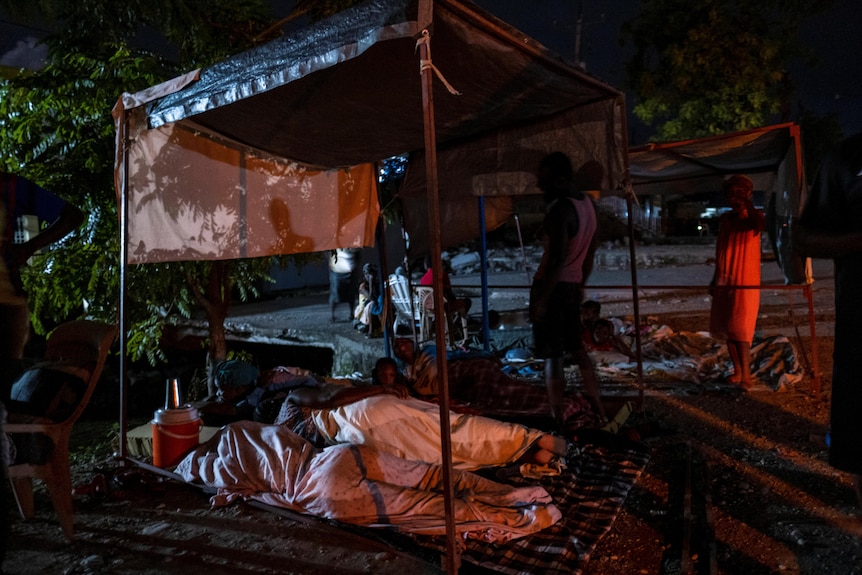 People sleep on sheets outdoors in Haiti
