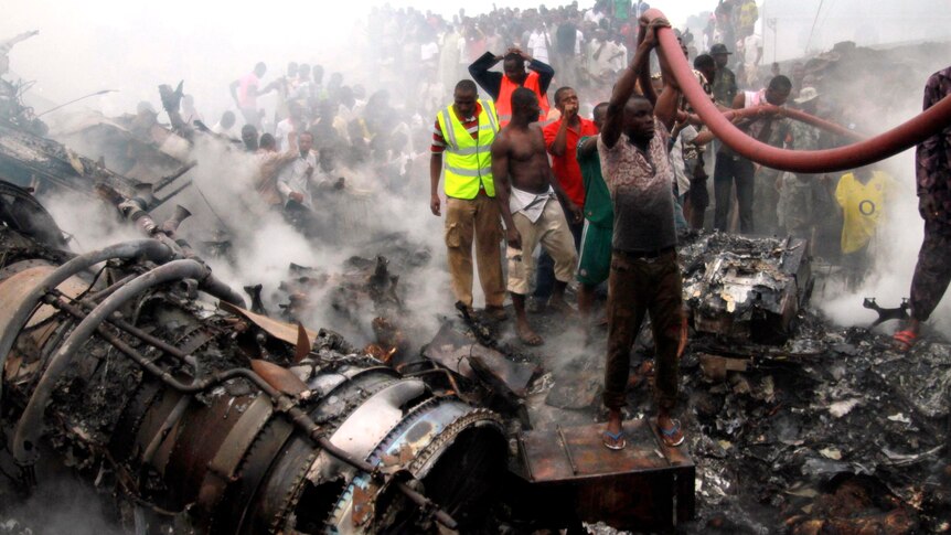 People help rescue workers pull a water hose after a plane crashed into a neighbourhood in Lagos.
