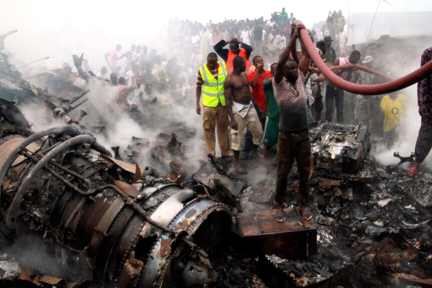 People help rescue workers pull a water hose after a plane crashed into a neighbourhood in Lagos.