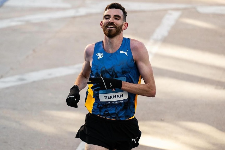a runner crosses the finish line og a marathon smiling