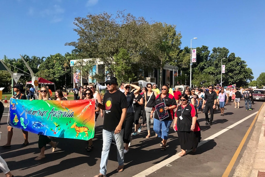 Groups of people walking down a street in Darwin as part of NAIDOC week.