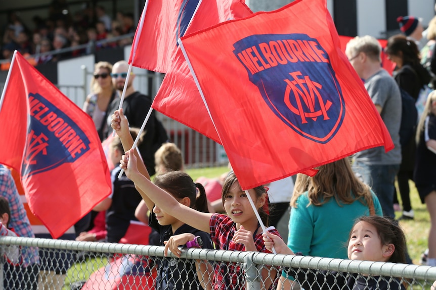 Melbourne fans wave flags at the Round 2 AFLW match between Collingwood and Melbourne at Victoria Park.