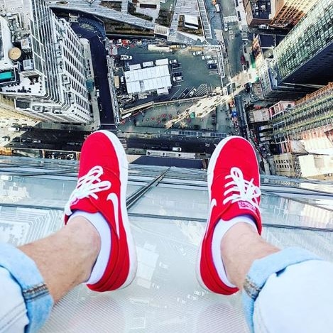 Legs of Jackson Coe dangling over a building in New York.
