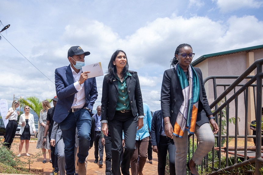 Three people, including Suella Braverman, walk up stairs outside a building in Rwanda