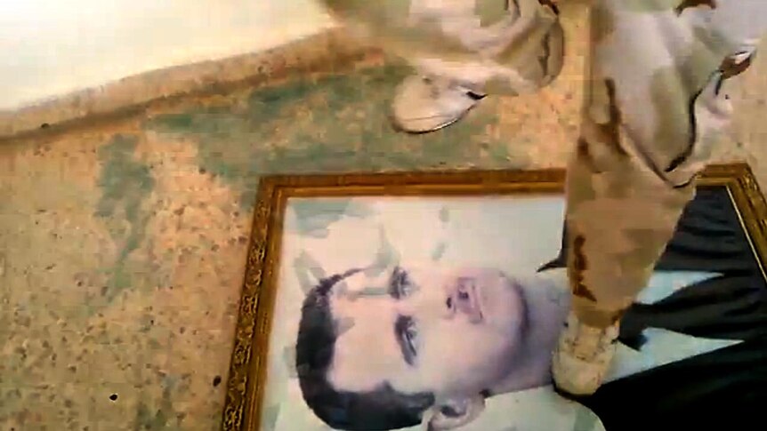A Free Syrian Army soldier stomps on a photo of Syrian president Bashar al-Assad at border crossing.