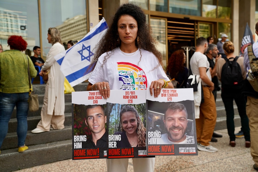 A woman stands with a sign saying 'bring her home' 