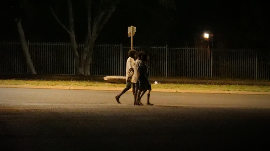 Children walk down a dimly lit outback street