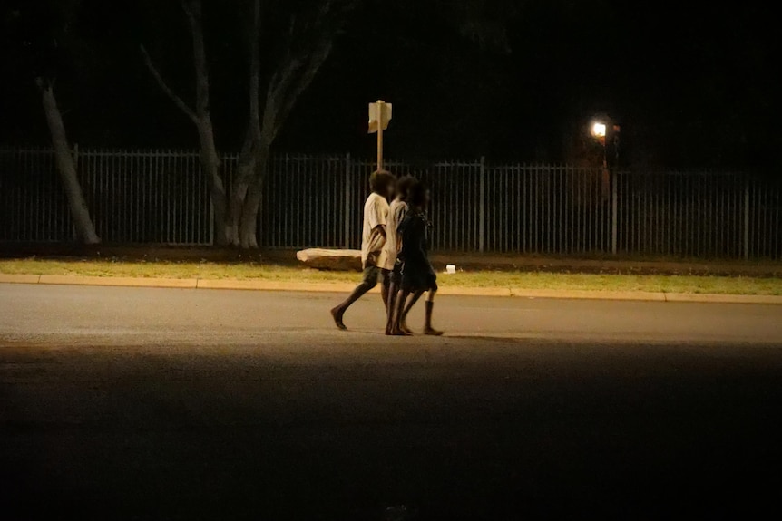 Children walk down a dimly lit outback street