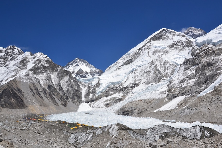 View of tents at Everest base camp with mountains, including Mount Everest (peak in far top right-hand corner), around