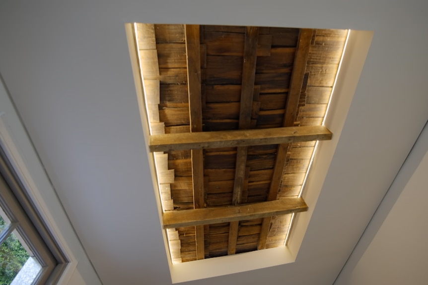 A view of a ceiling where an exposed section of old timber roof shingles is visible 