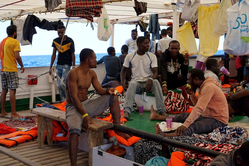 Migrants sit on the crowded deck of the Open Arms vessel.