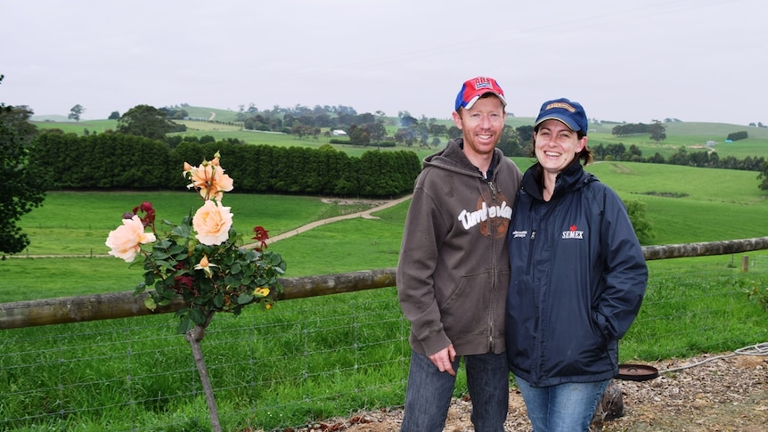 South Gippsland dairy farmers Luke and Melanie Wallace on their farm with green rolling hills.