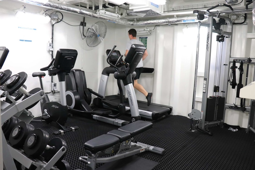 A man runs on a treadmill in the gym on HMAS Brisbane.