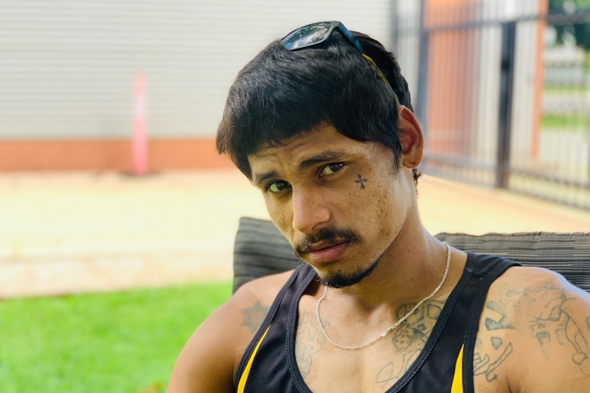 A man with dark hair and tattoos stares at the camera