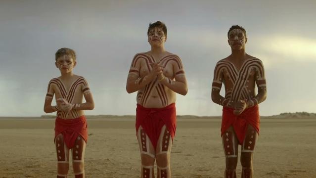 Three Indigenous boys stand with traditional body paint