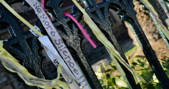 Coloured ribbons are tied to a fence outside a Ballarat church, with 'no more silence' writtten on one of them.