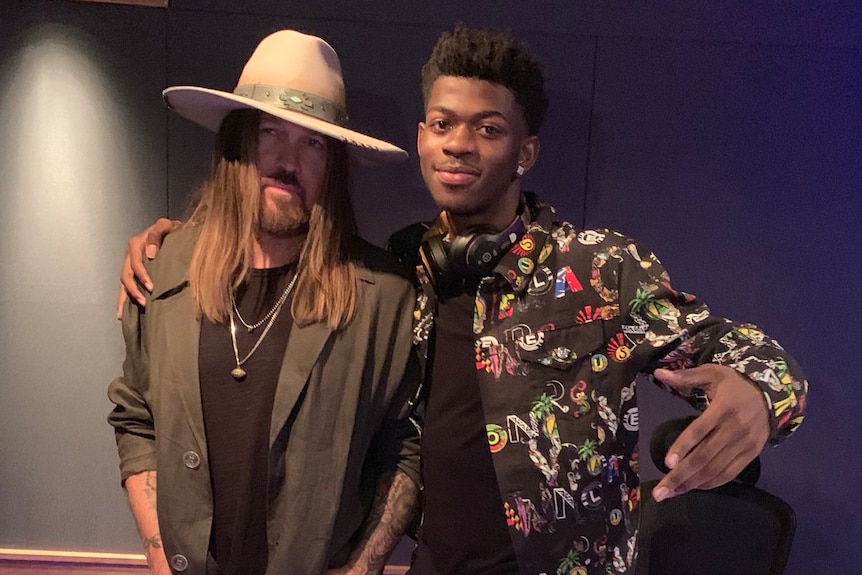 Lil Nas X stands with his arm around country music singer Billy Ray Cyrus.