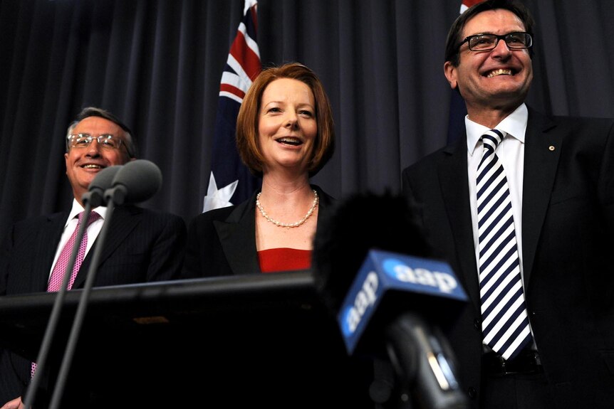 Wayne Swan, Julia Gillard and Greg Combet all smiles after carbon tax legislation is passed.