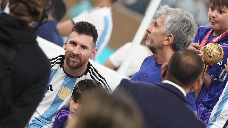 Lionel Messi viewed through the shoulders of others while his father, Jorge, looks away to his right after the World Cup final.