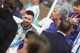 Lionel Messi viewed through the shoulders of others while his father, Jorge, looks away to his right after the World Cup final.