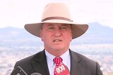 Barnaby Joyce wears a wide-brimmed hat and speaks towards the camera.