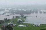 A view from above of floodwater surrounding farmland and houses.