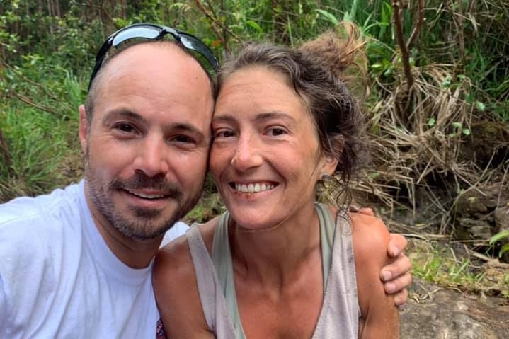 A man puts his arm around a woman who slightly dirty in a forest