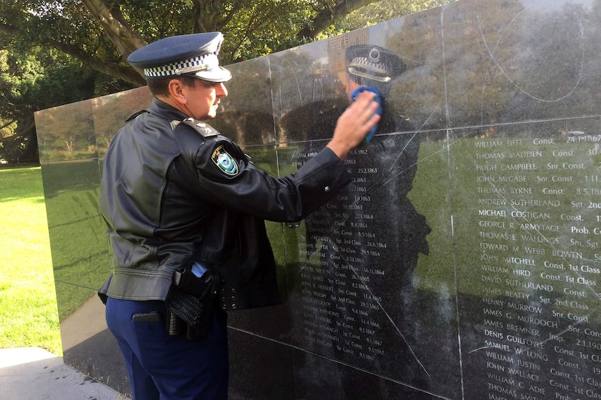 A police officer wipes the NSW Police Force Wall of Remembrance