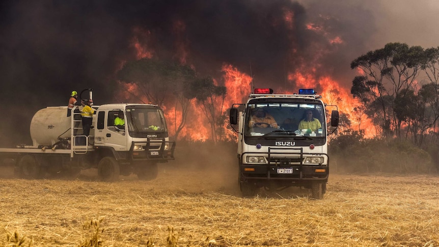 Firefighters in two trucks battle an out of control bushfire at Grass Patch near Esperance