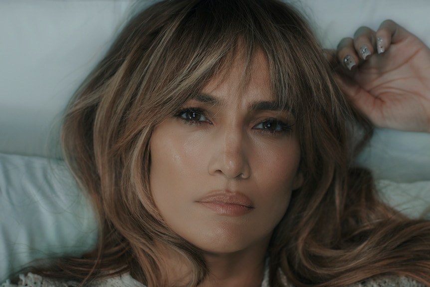 Close up on Jennifer Lopez's face as she lies in bed staring into the middle-distance.