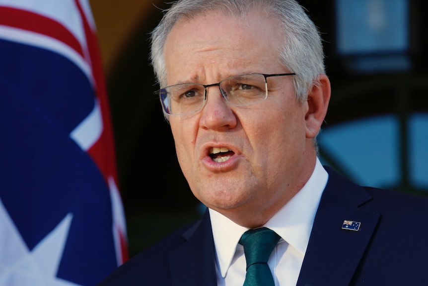 A close shot of Morrison speaking, with an Australian flag visible in the background.