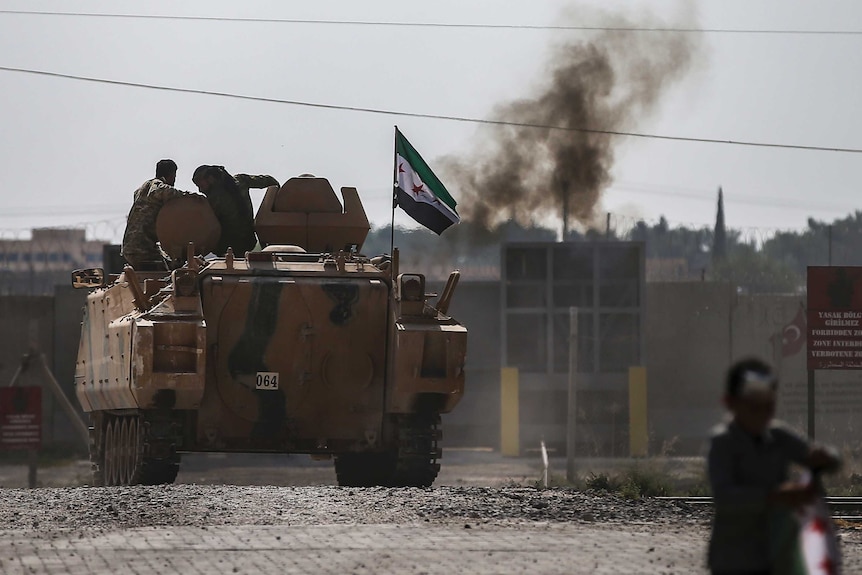 Syrian opposition fighters on an armoured personnel carrier in front of smoke