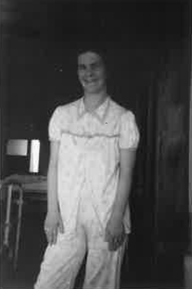 An old black and white photograph of a woman in a white dress.