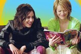 The L Word's Shane and Alice smile on a couch - Alice reads Girlfriend magazine. For a story about safe sex for queer women .