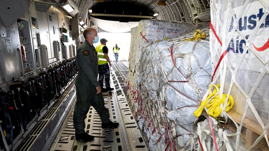 stack of humanitarian aid supplies with "Australian aid" written on the side, onboard an aircraft