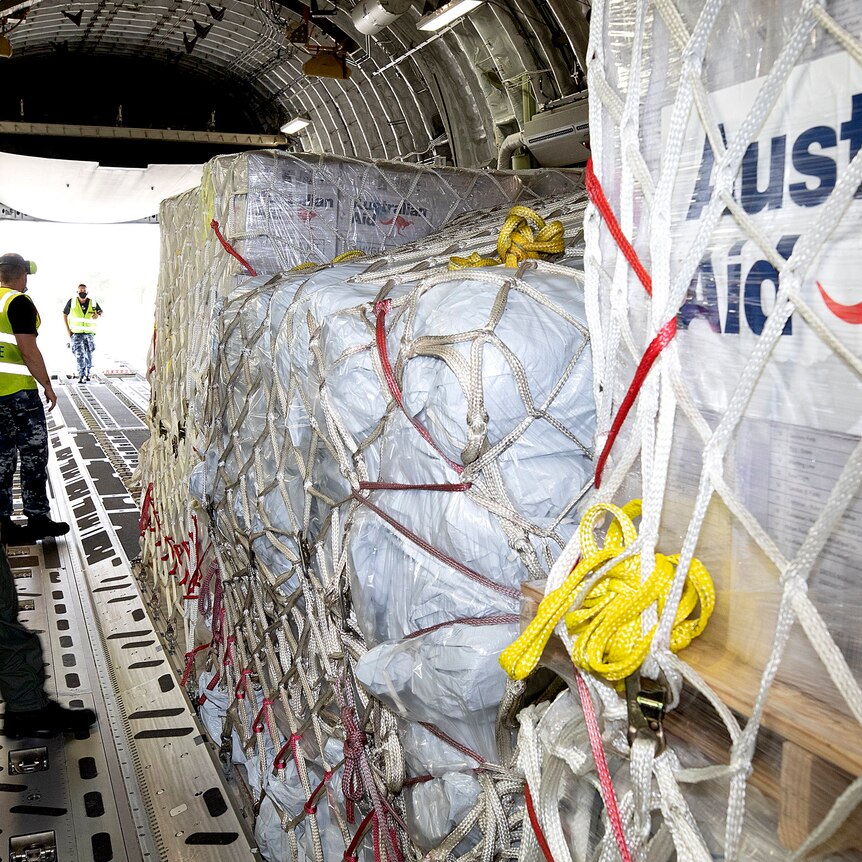 stack of humanitarian aid supplies with "Australian aid" written on the side, onboard an aircraft