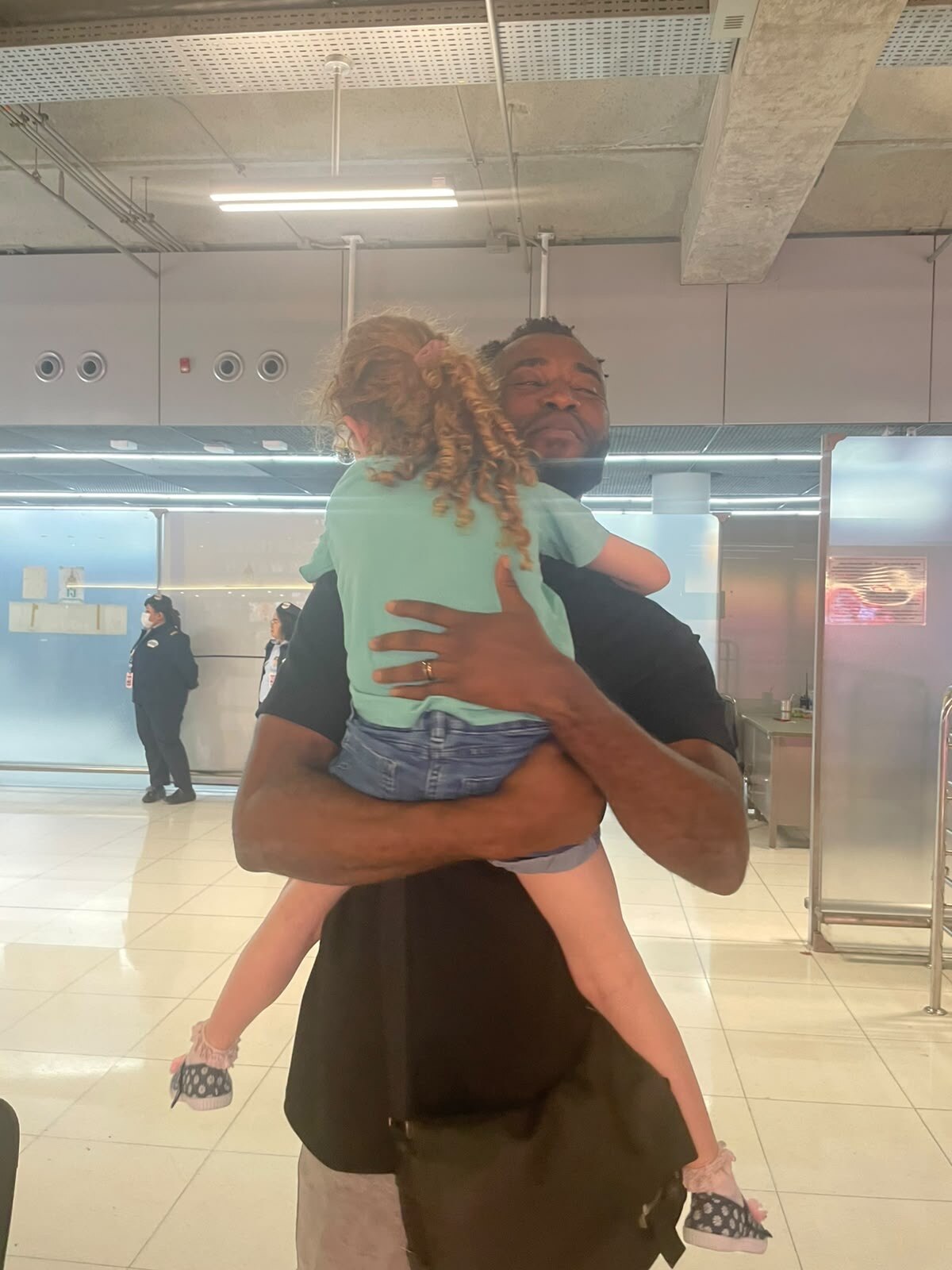 A man hug a little girl in a place that seems like a terminal
