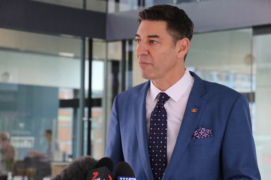 Basil Zempilas stands outside Council House. He wears a suit with a pocket square.