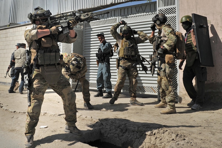 A member of the foreign forces points his gun towards a building in Kabul.