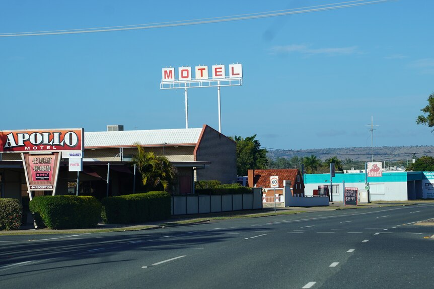 A white sign in a street says 'motel' in red lettering
