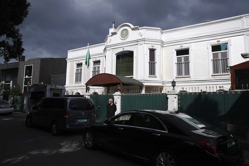 A man walks past the Saudi Arabia consul's residence in Istanbul. It is a big white building with a tall gate.