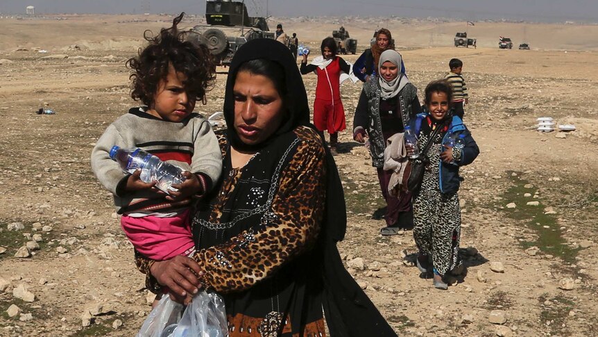 Displaced Iraqi women and children flee their homes due to fighting between Iraqi forces and IS in Mosul's west.