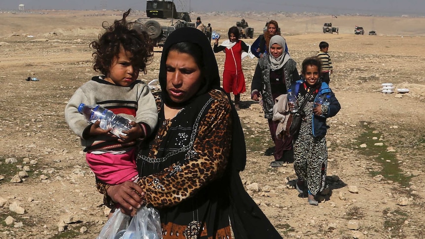 Displaced Iraqi women and children flee their homes due to fighting between Iraqi forces and IS in Mosul's west.