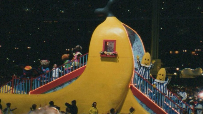 The Bananas in Pyjamas and other characters wave from a banana-shaped staircase float in Stadium Australia.