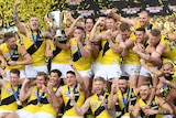 The Richmond players celebrate on the stage with the premiership cup as yellow and black confetti flies.