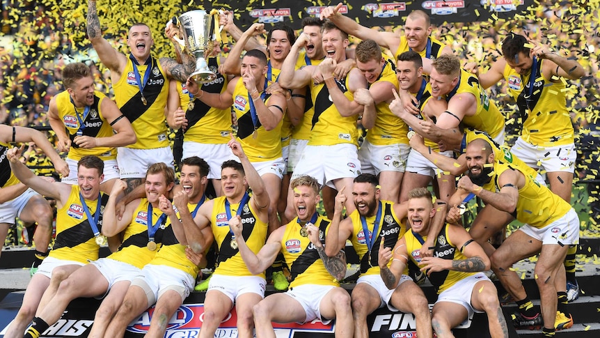 The Richmond players celebrate on the stage with the premiership cup as yellow and black confetti flies.