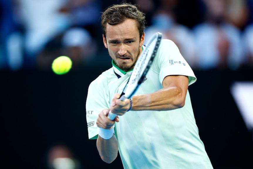 A Russian male tennis player hits a backhand return at the Australian Open.