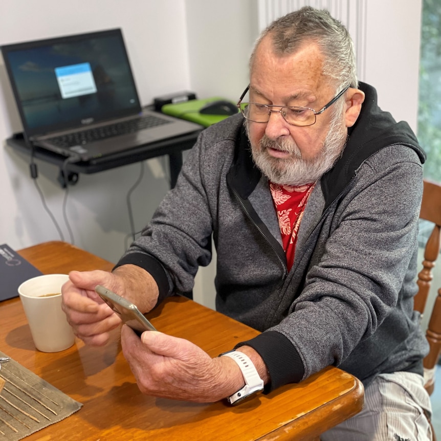 A man looks at his phone at his desk.