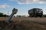 A Russian military truck drives past an unexploded munition.